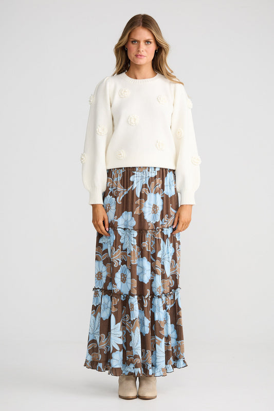 Woman wearing a white top and a long floral skirt on a white background