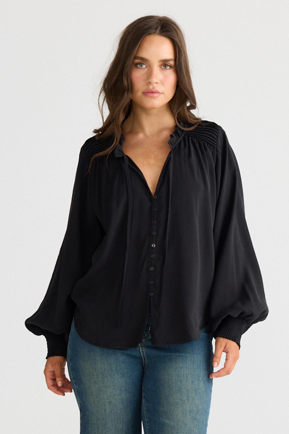 Close-up of Twilla Top in black showing round neckline and mini ruffle trim, detail view on white background