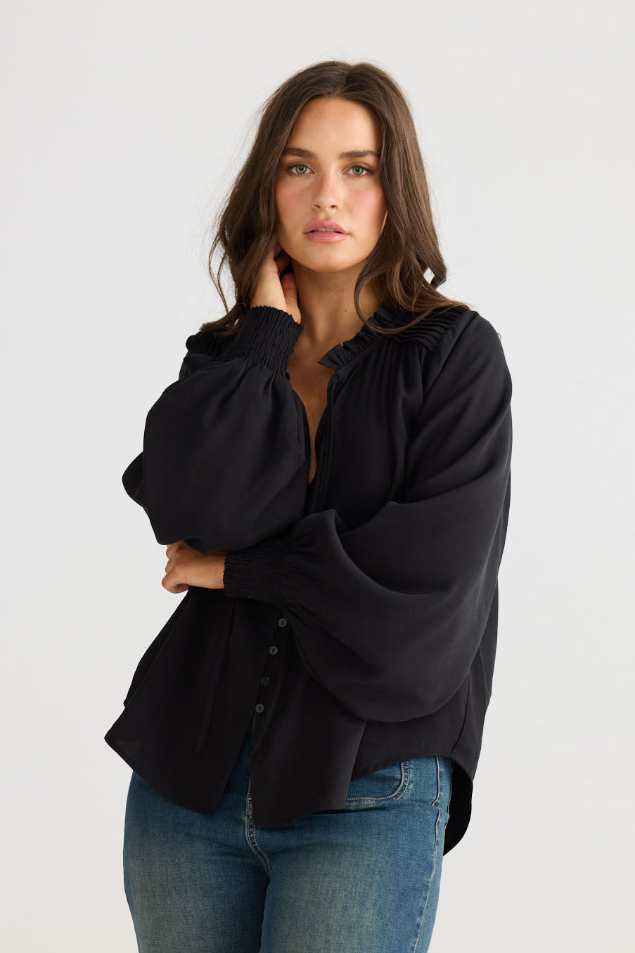 Model wearing Twilla Top in black with round neckline and mini ruffle trim, front view on white background