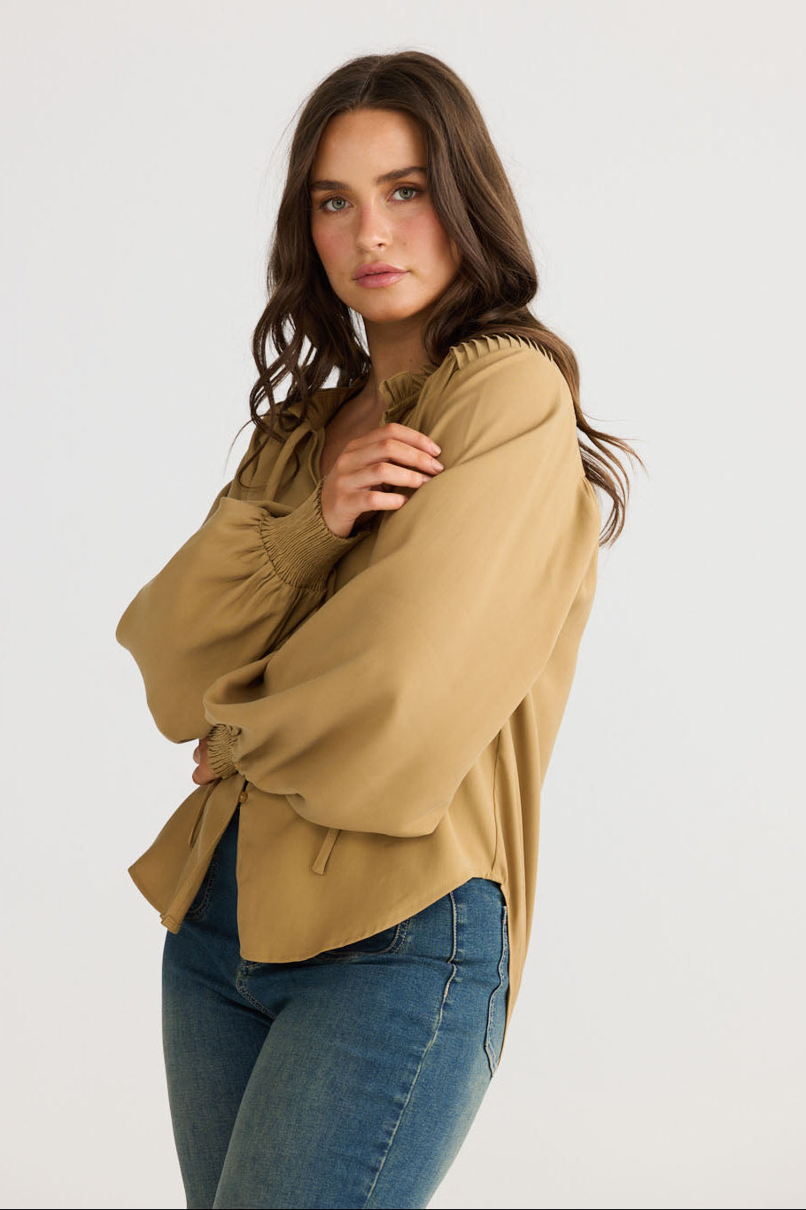 Model wearing Twilla Top in camel with round neckline and mini ruffle trim, front view on white background