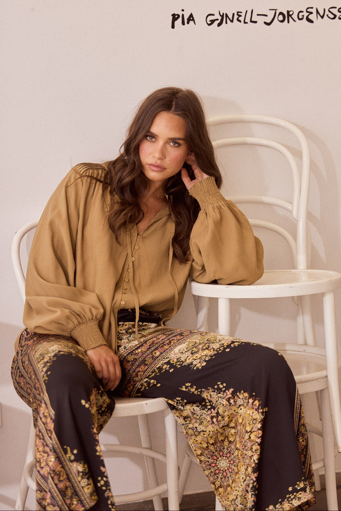Close-up of Twilla Top in camel showing round neckline and mini ruffle trim, detail view on white background
