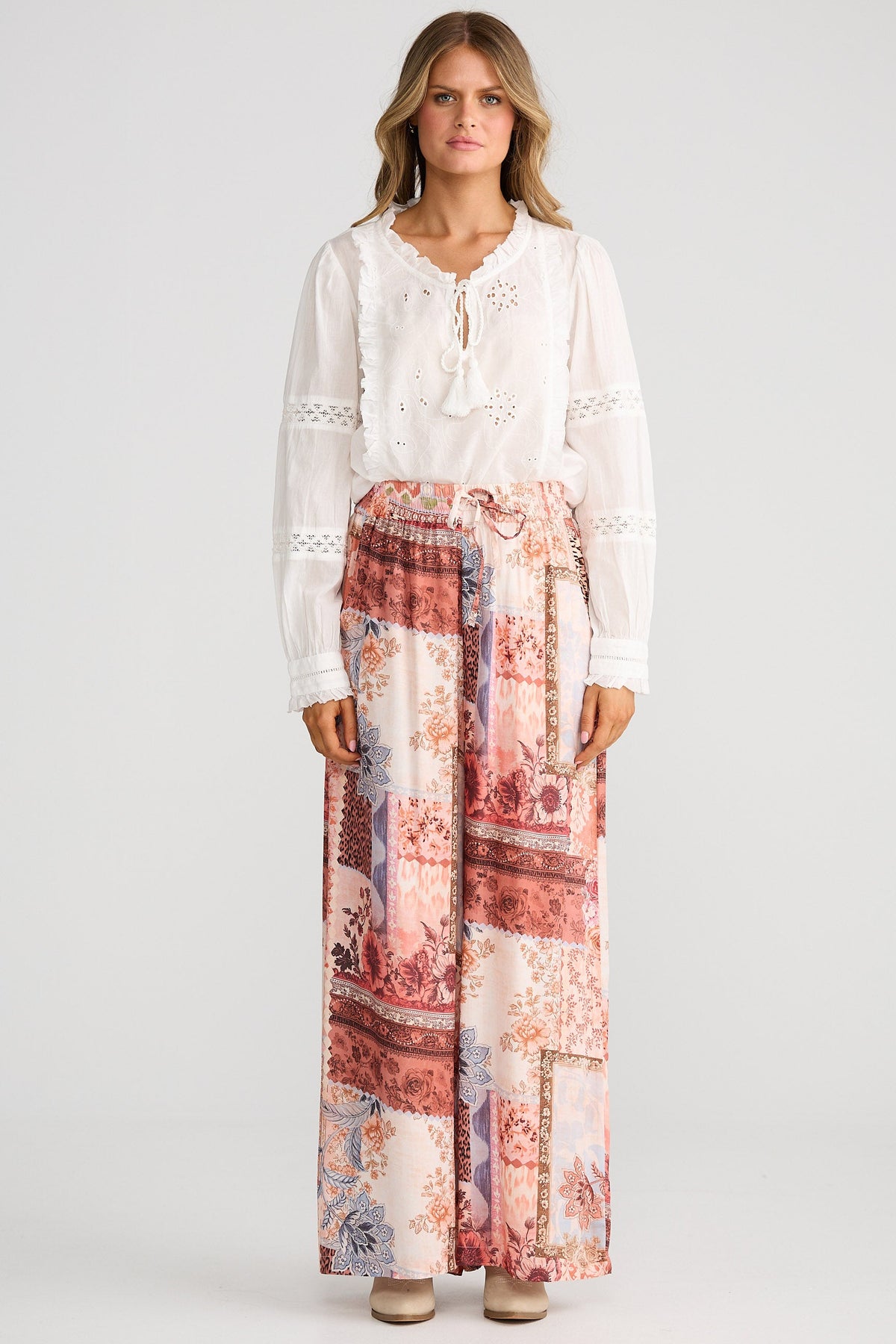 Woman wearing a white lace top and a long floral skirt on a white background