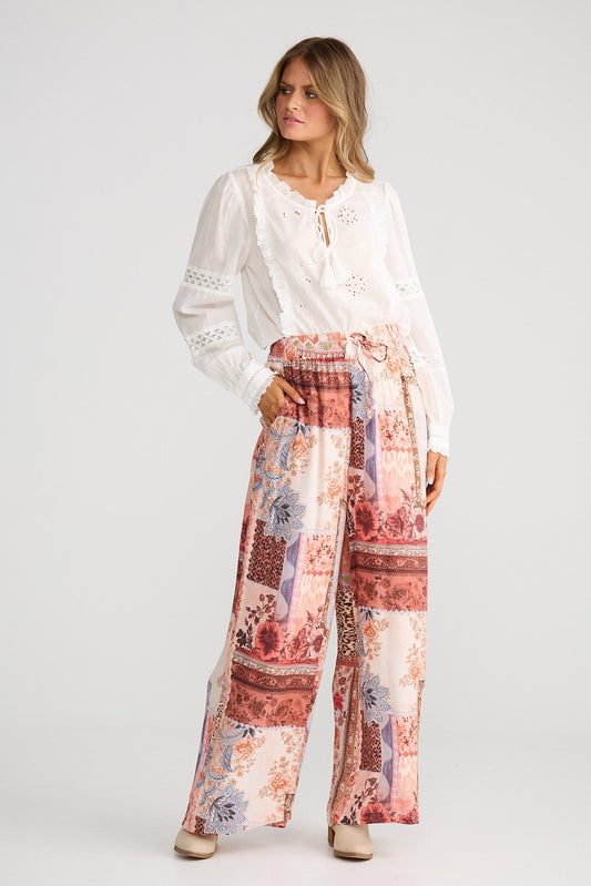Woman wearing a white blouse and patterned pants on a white background