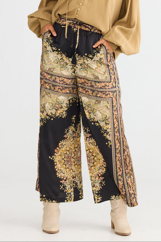 Model wearing Freedom Pant in black paisley with elasticated waistband and waist tie, back view on white background