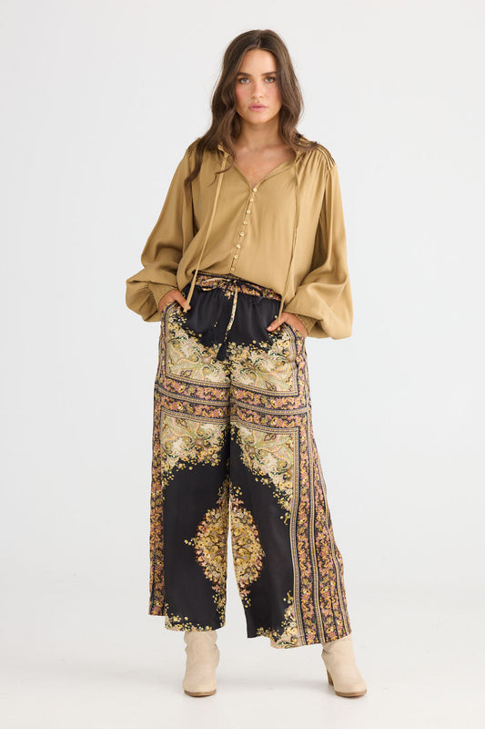Model wearing Freedom Pant in black paisley with elasticated waistband and waist tie, side view on white background