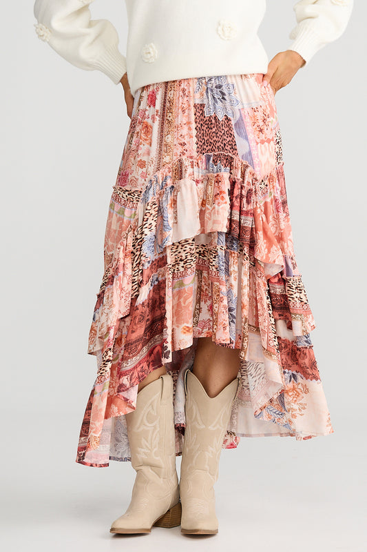 Person wearing a patterned skirt and beige boots on a white background
