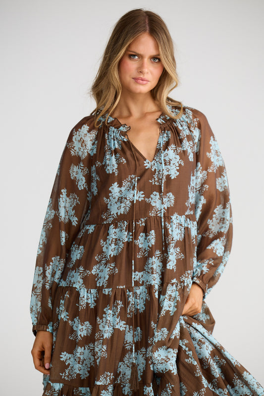 Woman wearing a brown floral dress against a white background