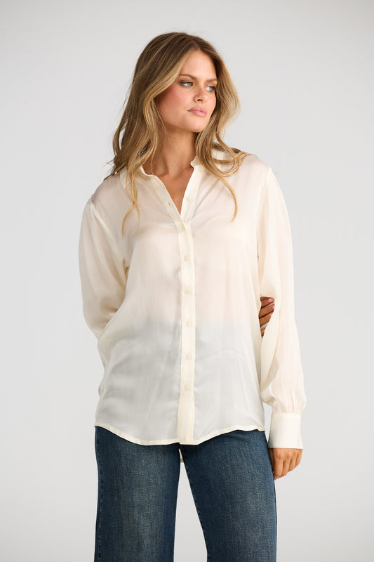 Woman wearing a white blouse with a gradient effect and blue jeans on a plain background