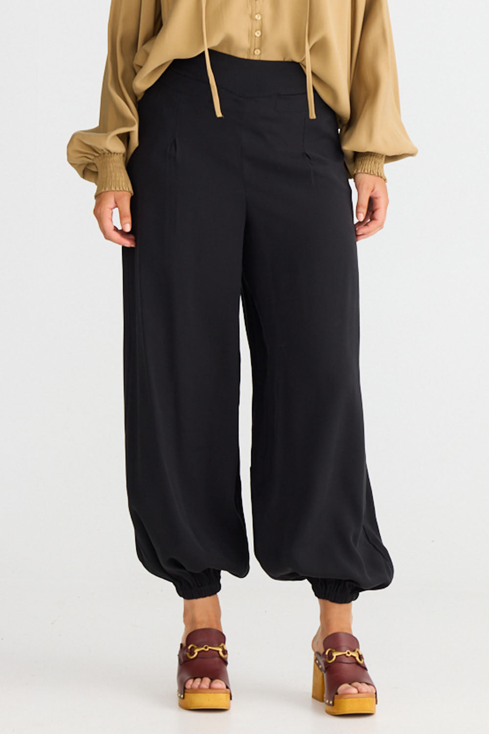 Model wearing Genie Pant in black with elasticated back waistband, front view on white background