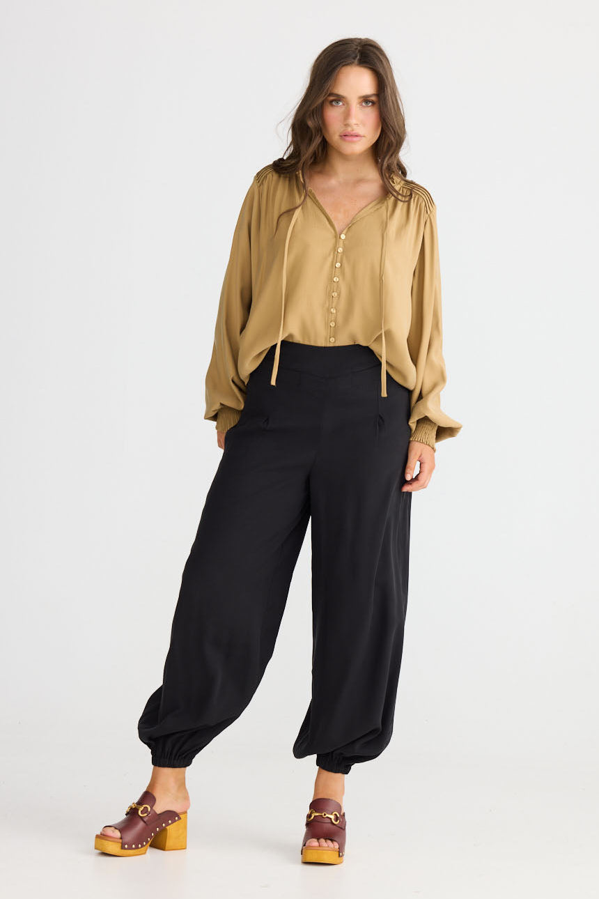 Model wearing Genie Pant in black with elasticated back waistband, front view on white background