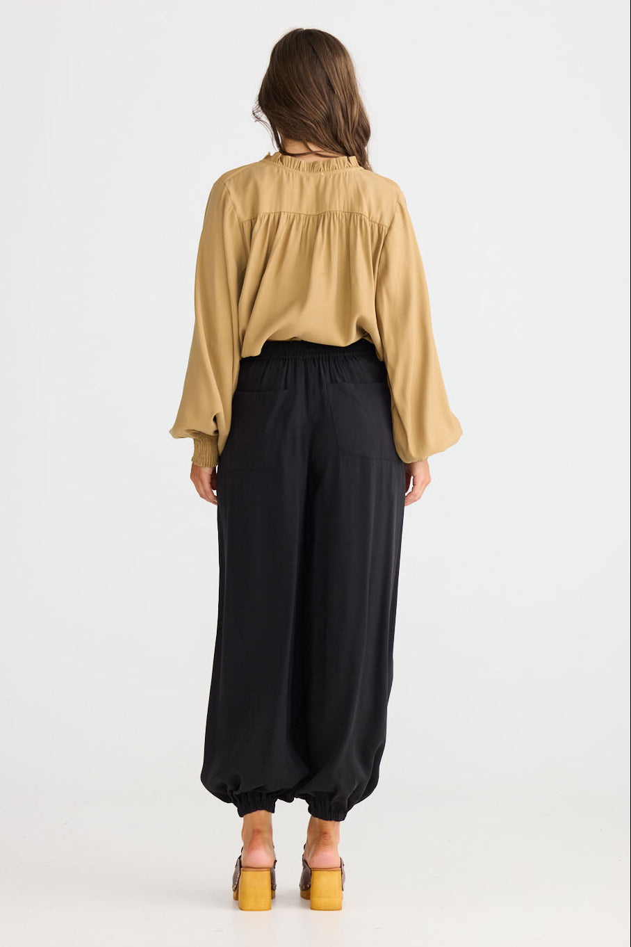 Model wearing Genie Pant in black with elasticated back waistband, side view on white background