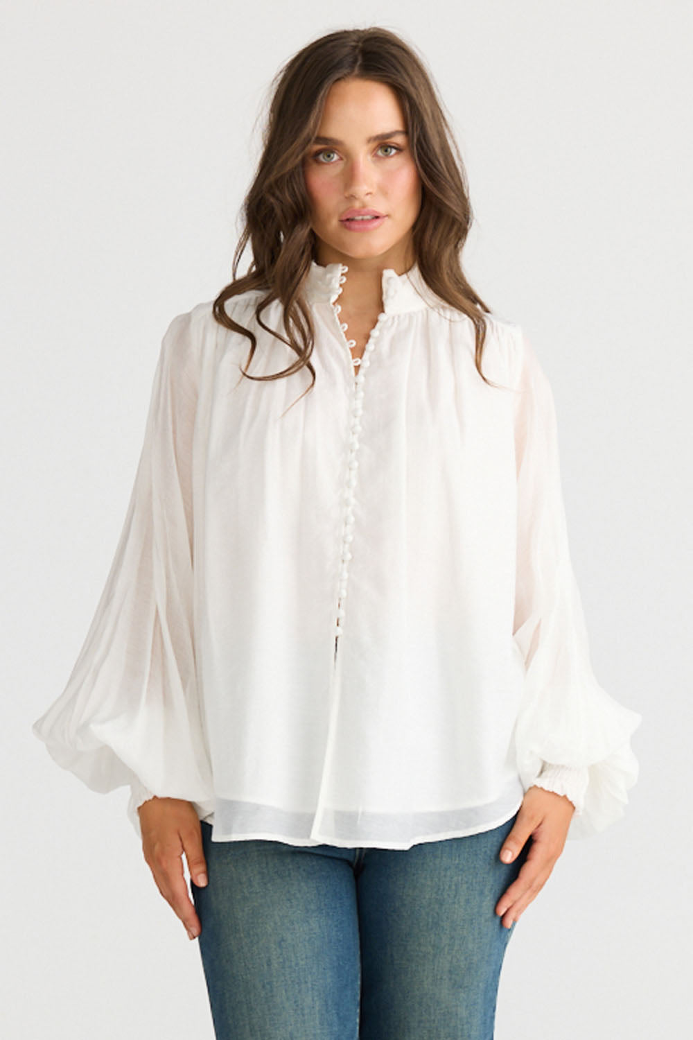 Model wearing Sylva Blouse in off white with high collar with ruched details, front view on white background