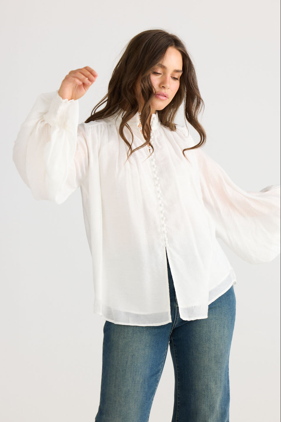 Model wearing Sylva Blouse in off white with high collar with ruched details, side view on white background