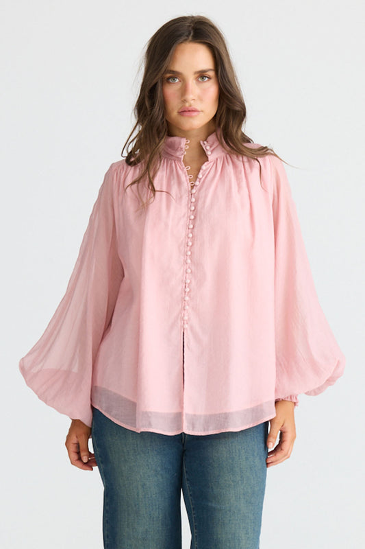Model wearing Sylva Blouse in pink with high collar with ruched details, front view on white background