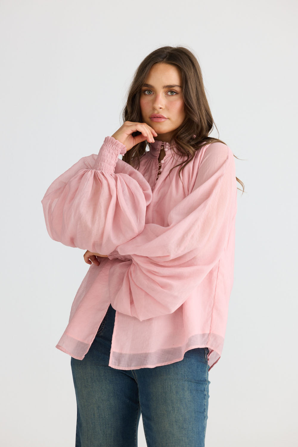 Model wearing Sylva Blouse in pink with high collar with ruched details, front view on white background