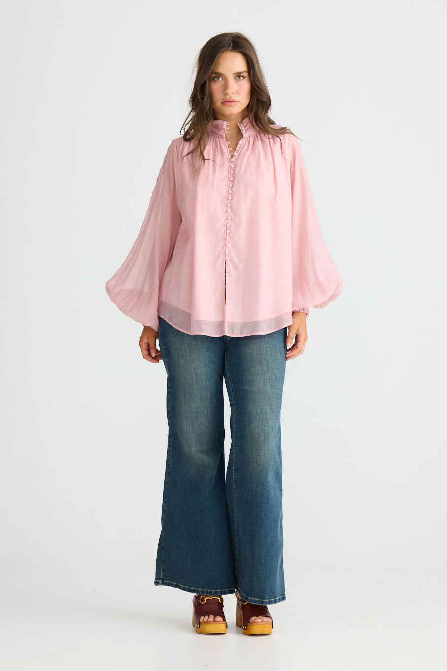 Model wearing Sylva Blouse in pink with high collar with ruched details, back view on white background