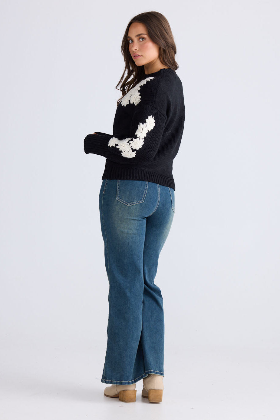 Model wearing Flower Child Knit in black and white with round neckline and extra wide cuffs, side view on white background