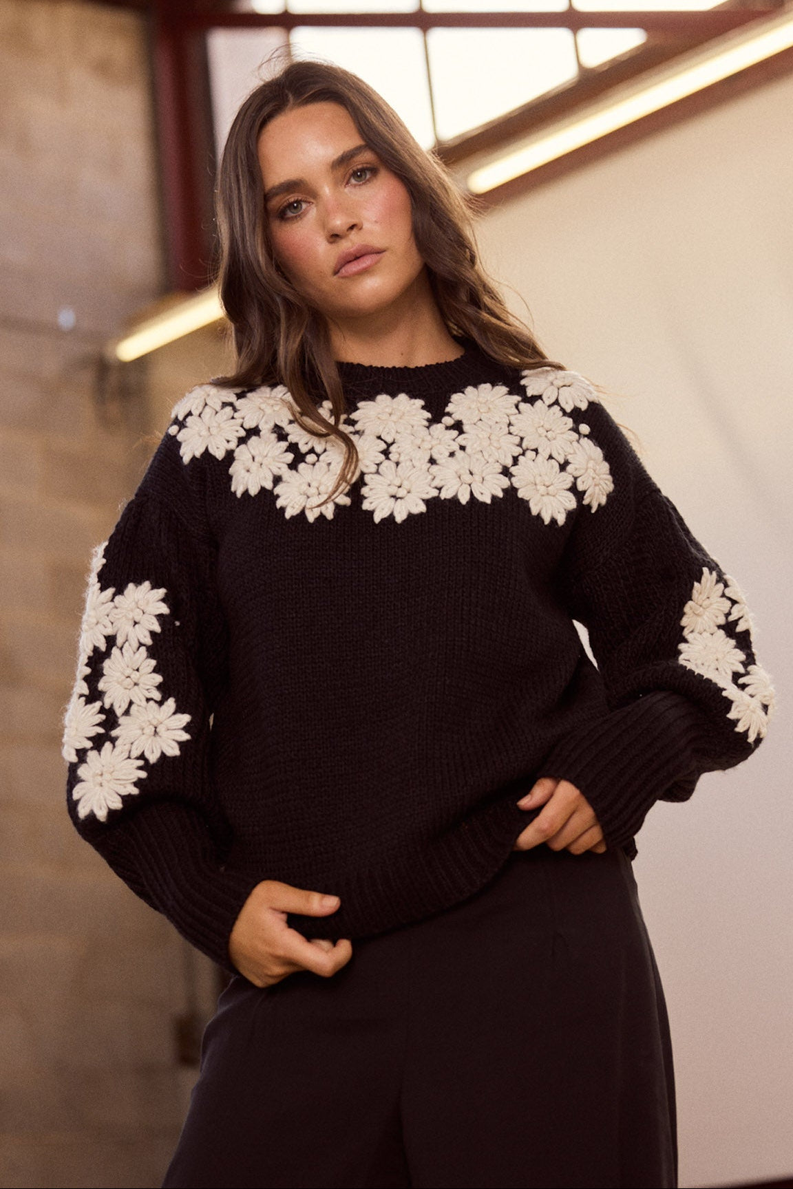 Model wearing Flower Child Knit in black and white with round neckline and extra wide cuffs, side view on white background