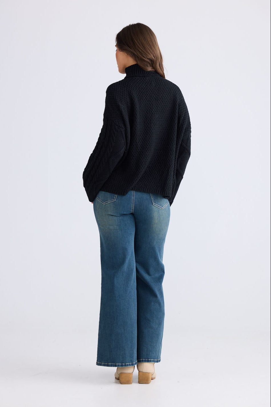 Close-up of Dixie Knit in black showing roll-neck collar and cable knit design, detail view on white background