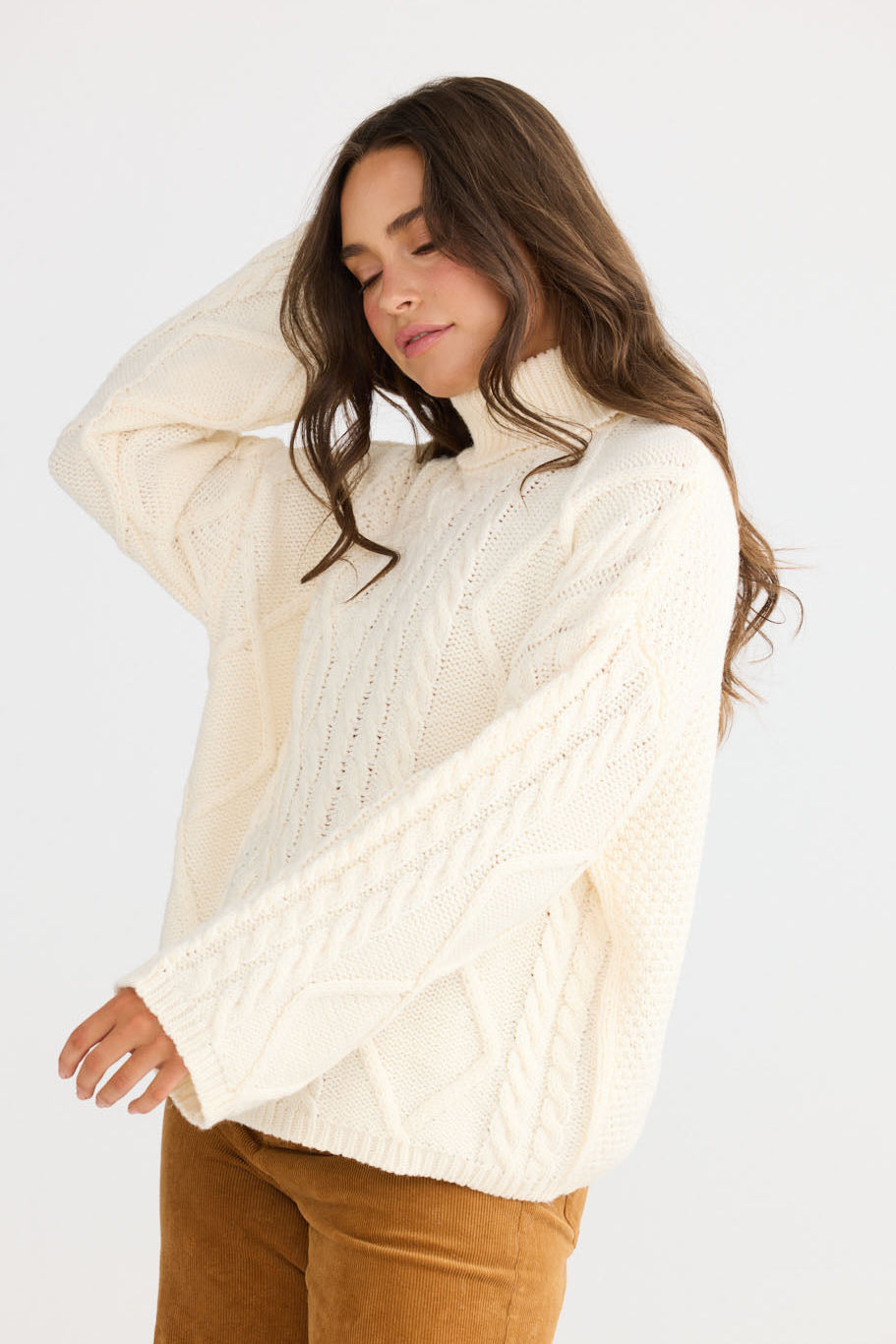 Close-up of Dixie Knit in cream showing roll-neck collar and cable knit design, detail view on white background
