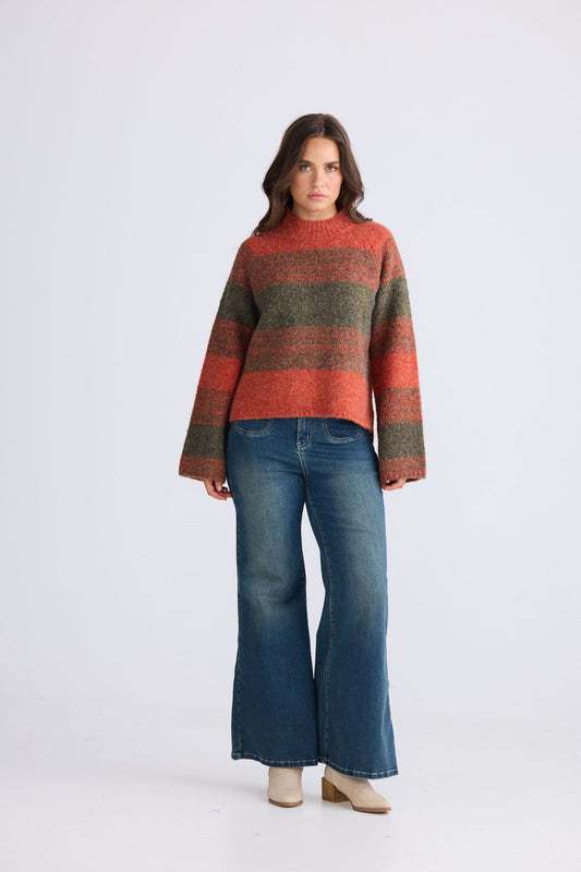 Model wearing Vesper Knit in orange and green with wide long sleeves and side splits, side view on white background