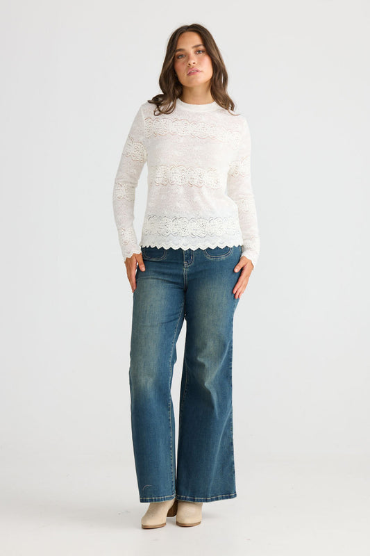 Model wearing Liora Top in white with crew neckline and long fitted sleeves, front view on white background