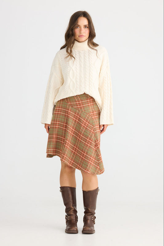 Model wearing Runa Skirt in rust check with natural waist fit, side view on white background