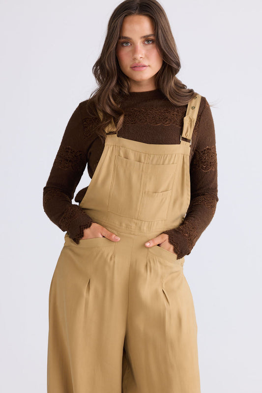 Model wearing Genie Overalls in camel, front view on white background
