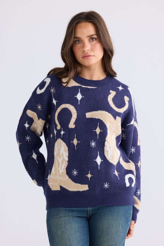 Model wearing Lucky Boots Knit in navy with ribbed neckline and cowboy-themed print, front view on white background