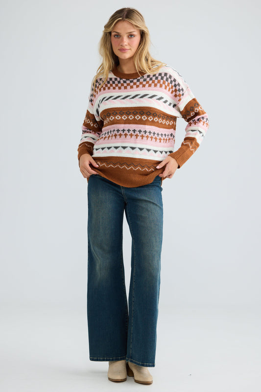 Woman wearing a patterned sweater and blue jeans on a white background