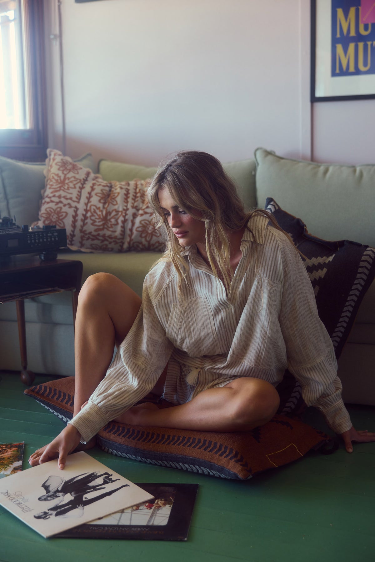 Bodhi Shirt in natural stripe, seated on a rug at home among records.