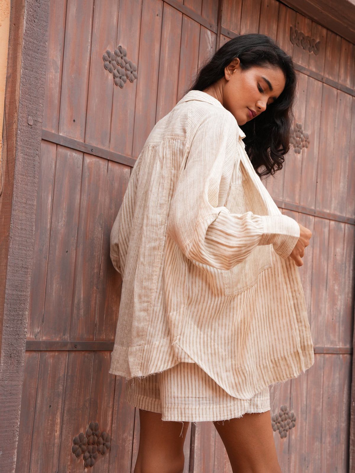 Bodhi Shirt and Bodhi Short in natural stripe, side view adjusting the shirt.