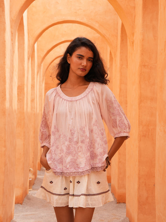Thistle Top in soft pink with the Saskia Short, front view in a sunlit terracotta arcade.