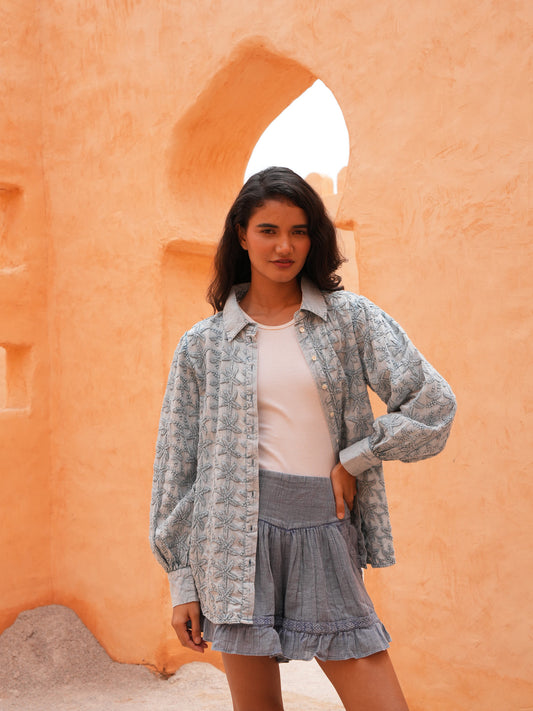 Flower Child Shirt in powder blue worn open with the Ithika Short, front view against a terracotta wall.