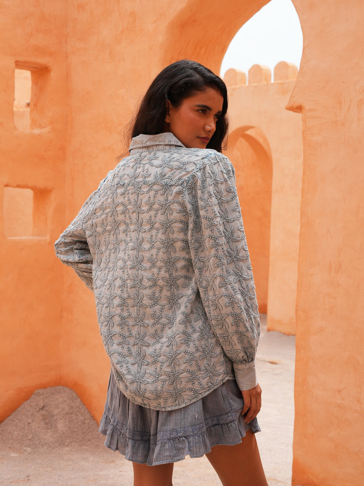 Flower Child Shirt in powder blue, back view in a terracotta archway.