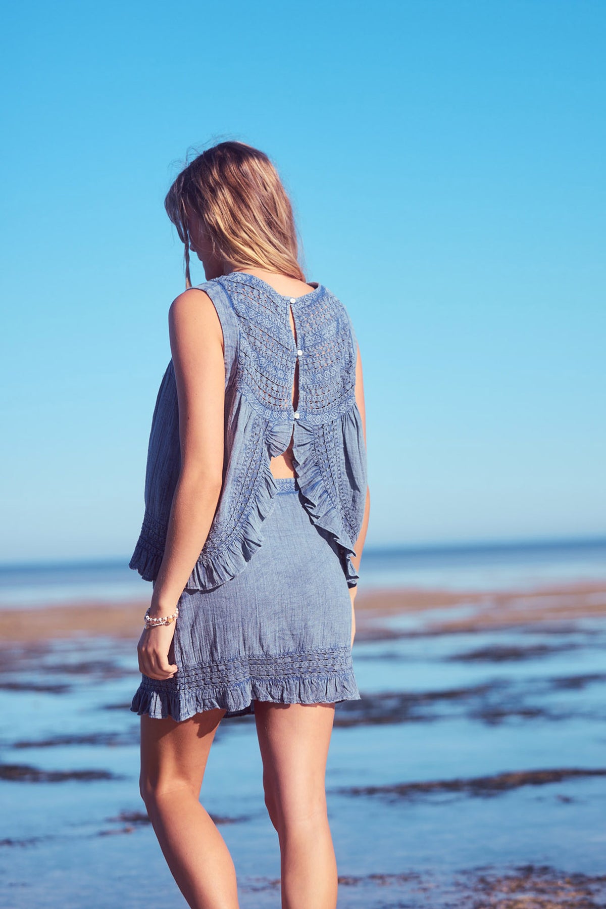 Freesia Top in steel blue, back view on the shore.