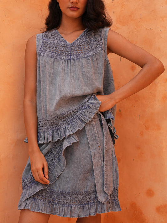 Freesia Mini Wrap Skirt in steel blue, close crop with the Freesia Top against a terracotta wall.