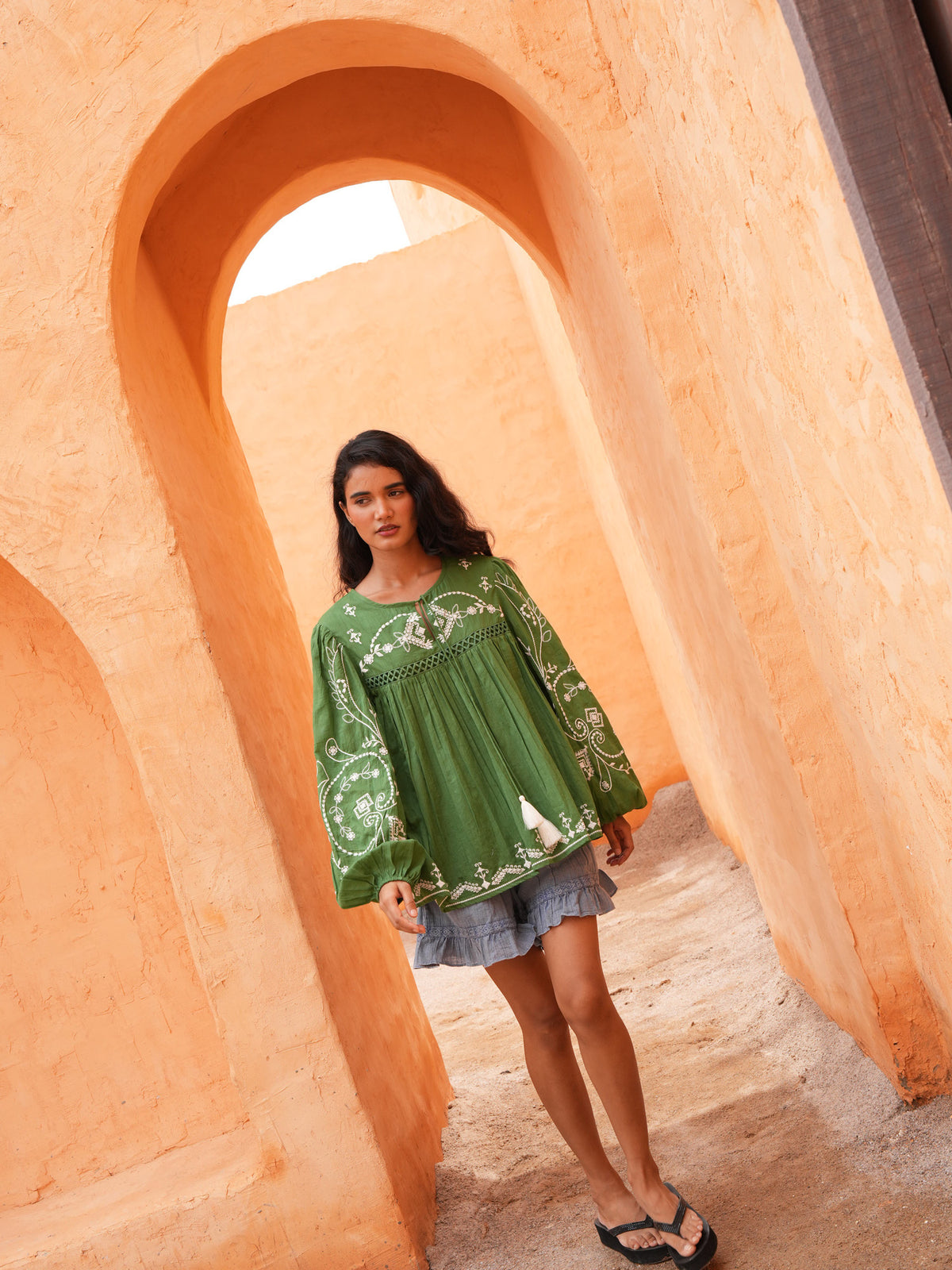 Ithika Short in steel blue with the Sapphire Top, full length in a terracotta archway.