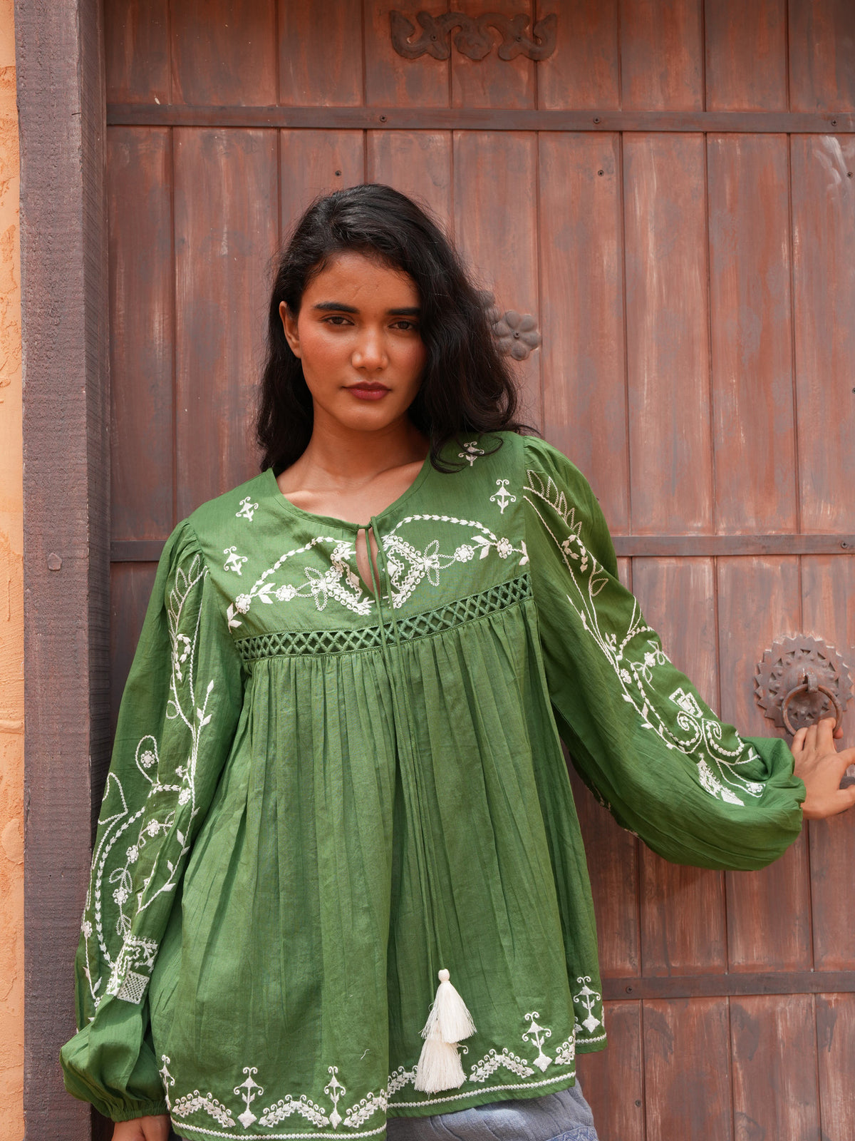 Sapphire Top in olive, close front view at a timber door.