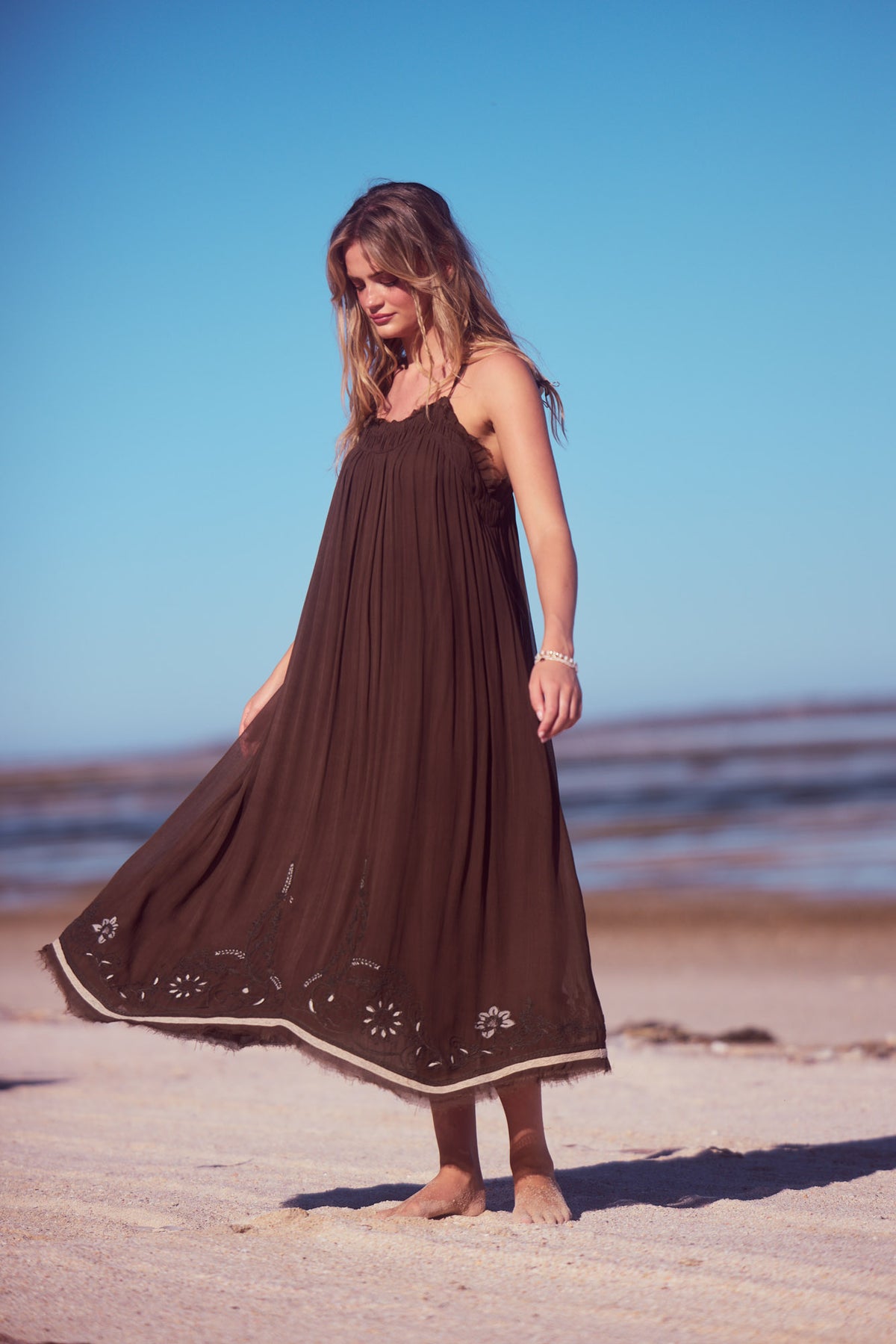 Ambrosia Maxi Dress in cocoa, twirling the skirt on the beach.