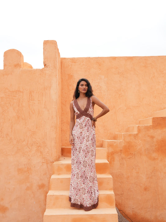 Luca Dress in chai floral, full length on sunlit terracotta stairs.