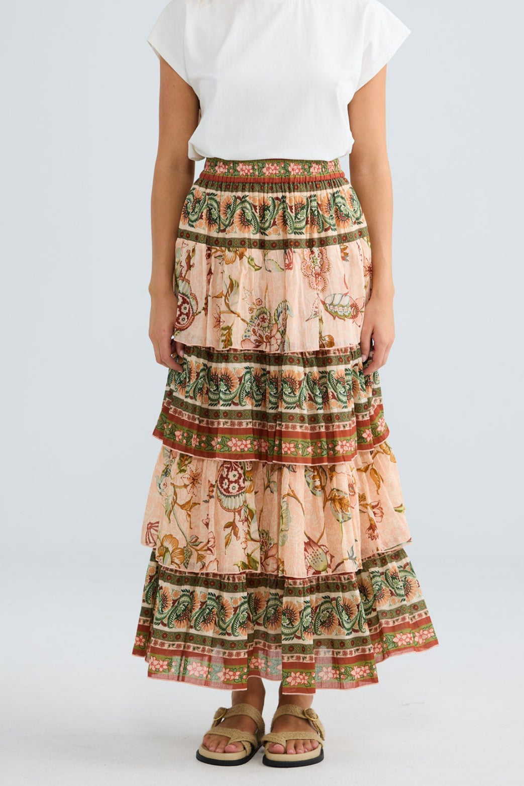 Woman wearing a patterned skirt and white top on a plain background