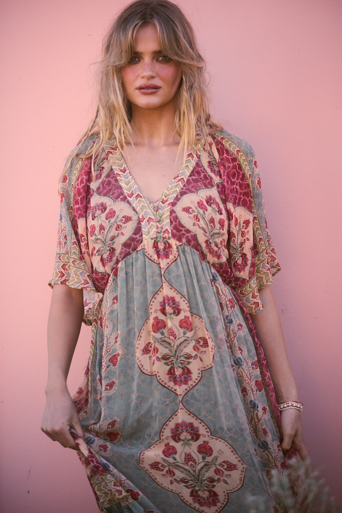 Tulara Dress in garden mist, close portrait against a pink wall.
