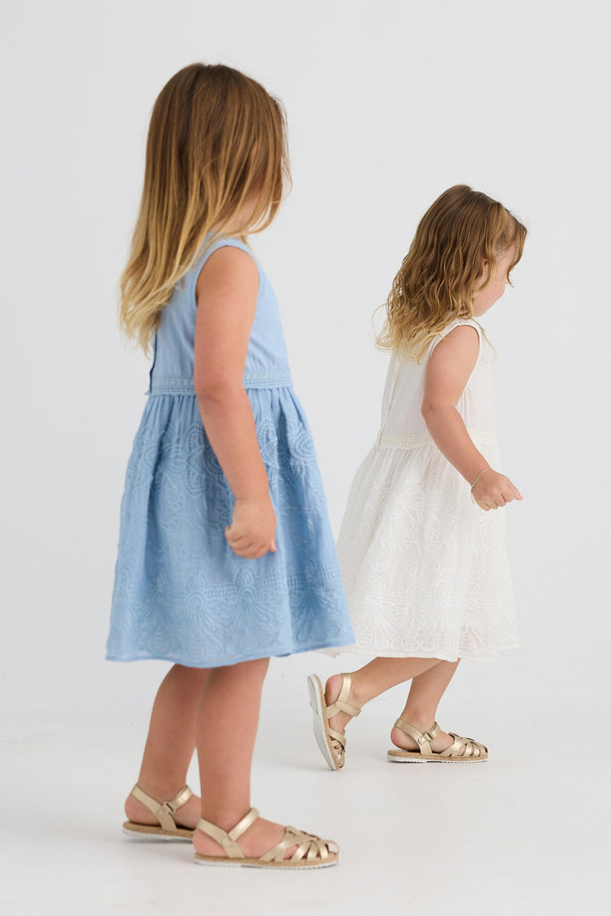 Two young girls wearing dresses on a white background