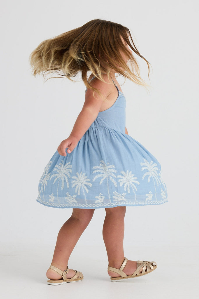 Young girl in a blue dress with white patterns on a white background