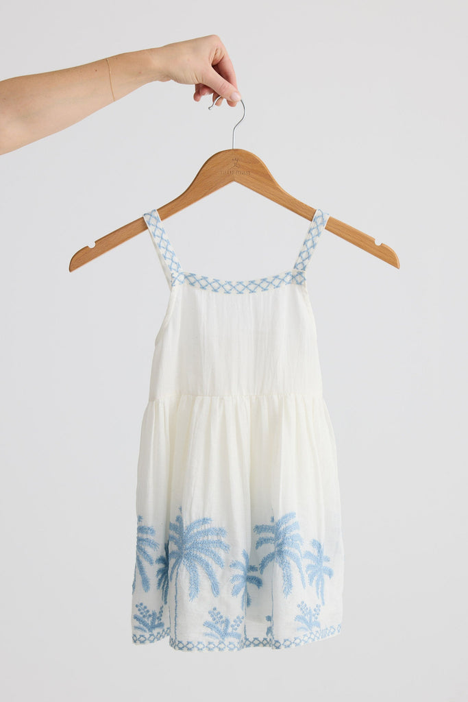 White dress with blue floral patterns on a hanger against a white background