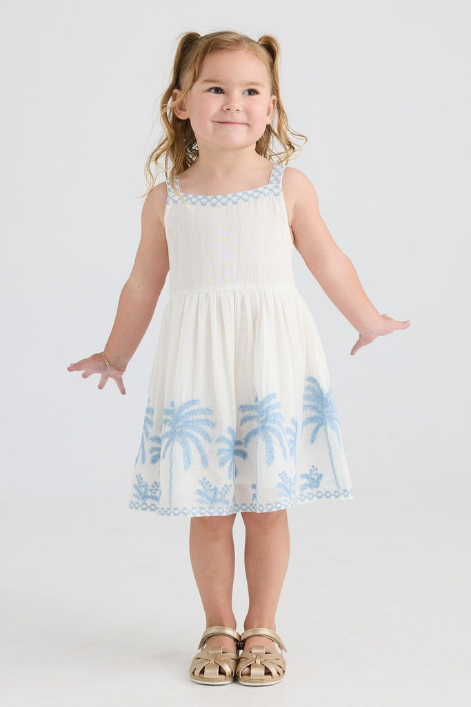Young girl wearing a white dress with blue floral patterns on a white background