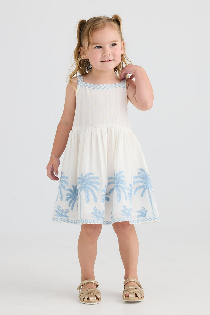 Young girl wearing a white dress with blue floral patterns on a white background