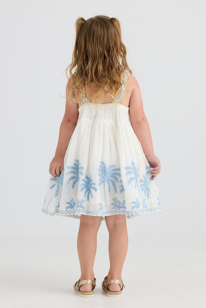 Young girl wearing a white dress with blue floral patterns on a white background