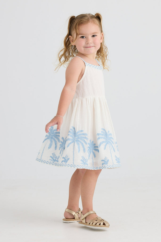 Young girl wearing a white dress with blue floral patterns on a white background